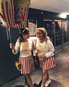 two women dressed in costumes holding popcorn buckets