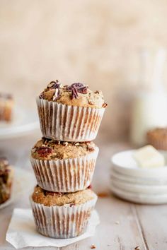 three muffins stacked on top of each other with cranberries and pecans in the background