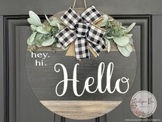 a door hanger that says hey hi hello with green leaves and greenery on it