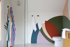 a bathroom with colorful wallpaper and towels hanging on the rack next to the toilet