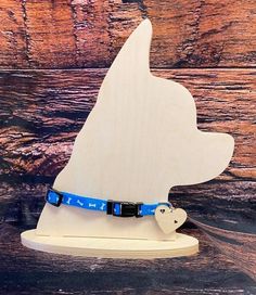 a wooden dog head with a blue leash on it's collar is shown against a wood background