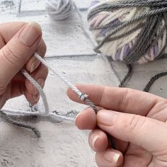 two hands are holding yarn and pulling on the end with their thumbnails, while another hand is knitting