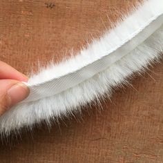 a person holding a white feather on top of a wooden table