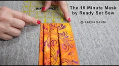 the woman is using scissors to sew an orange piece of fabric with pink and purple designs on it