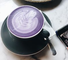 there is a cup of coffee on the table with a cell phone next to it