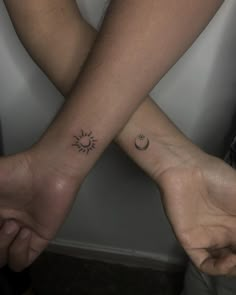 two people are holding hands with tattoos on their arms and one has a sun and moon