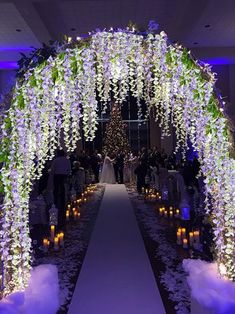 an archway decorated with flowers and candles is lit up for a wedding ceremony at night