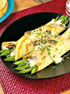 asparagus and mushroom crepes on a black plate with red placemat