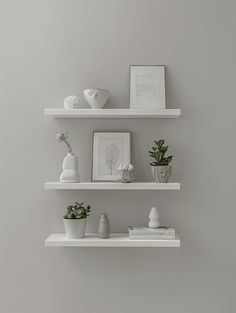 three white shelves with plants and pictures on them