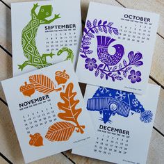 three calendars with different designs on them sitting next to each other in front of a wooden table