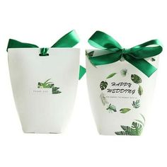 two white bags with green ribbons tied around them, one has a happy wedding message on it