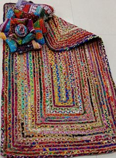 a multicolored rug is laying on the floor next to a pile of blankets