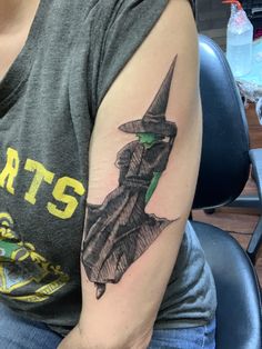 a woman sitting in a chair with a tattoo on her arm that has a wizard's hat on it