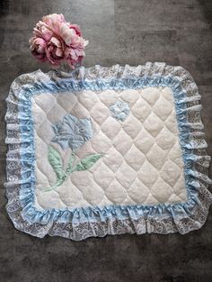 a pink flower sitting on top of a table next to a blue and white quilt