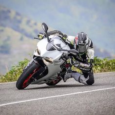 a man riding on the back of a silver motorcycle down a curvy road