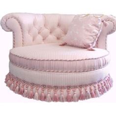 a pink chair with tassels and pillows on it