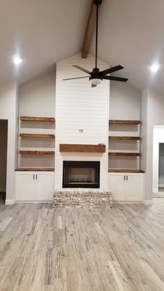 an empty living room with white walls and wood flooring on the wooden floor is a ceiling fan