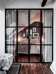 an open glass door leading to a bedroom with a bed in the corner and wooden floors