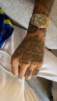 a man with tattoos on his arm and wrist is holding onto a watch while sitting in bed