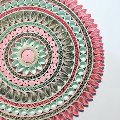 a pink and green circular design made out of plastic cups on a white surface with an object in the middle