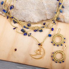 This pretty jewelry set from Alejandra Torres in Mexico features celestial blue shades complemented by gleaming gold. Multiple strands of crocheted golden metallic thread host polished chips of lapis lazuli to form the necklace which is centered by an 18k gold-plated brass moon and star pendant. The earrings are crafted from crocheted golden thread hoops that are accented with tiny lapis lazuli beads. The necklace clasp and earring hooks are 18k gold plated brass. Celestial Blue Beaded Jewelry, Bohemian Gold Lapis Lazuli Necklace, Celestial Gold Beaded Jewelry, Gold Bohemian Jewelry With Lapis Lazuli, Gold Bohemian Lapis Lazuli Jewelry, Bohemian Gold Lapis Lazuli Jewelry, Gold And Blue Jewelry, Moon And Star Pendant, Crocheted Jewelry