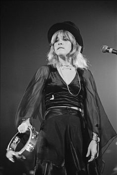 a woman in a black dress and hat on stage