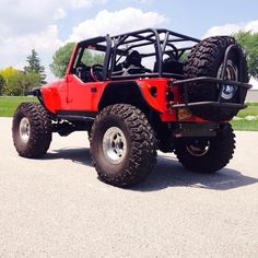 a red jeep with four wheels parked in a parking lot