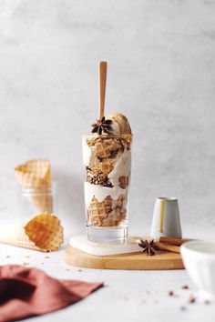 an ice cream sundae with nuts and cinnamons in it on a wooden board