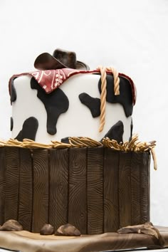 a chocolate cake with white and black frosting on a wooden stand, topped with a cow's head