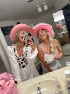 two women wearing pink hats are taking a selfie in front of the bathroom mirror