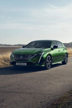 a green car driving down a road in the middle of an open desert area with dry grass