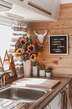 a kitchen counter with flowers in a vase and a cow skull mounted on the wall