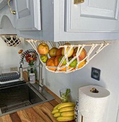 a kitchen sink under a hanging basket filled with fruit