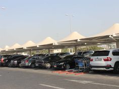 a parking lot filled with lots of cars next to tall white tents on top of each other