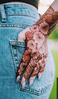 a woman's hand with henna tattoos on her left arm and the bottom half of