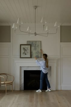 a woman standing in front of a fire place with her hand on the fireplace mantel