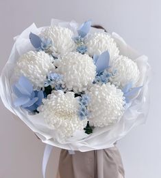 a woman holding a bouquet of white and blue flowers