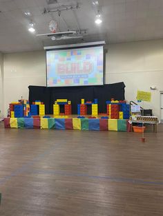 an indoor play area for children with blocks on the floor and a projector screen in the background