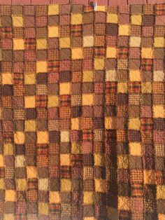 an orange and brown checkered blanket hanging on a wall