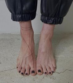 a woman's bare feet with black nail polishes on her toes and one foot in the air