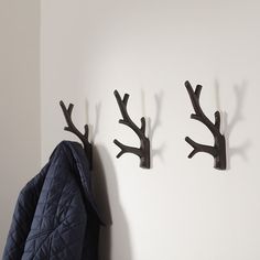 two coat hooks are mounted to the wall with deer antlers on them, and one has a blue jacket hanging from it