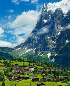 the mountains are covered in snow and green grass, with houses on each side below them