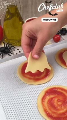 someone is spreading cheese on top of small pizzas