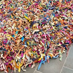 a pile of multicolored shredded paper on the ground next to a tiled floor