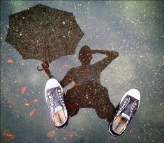 a person standing under an umbrella in the rain with their feet up on the ground