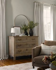 a living room filled with furniture and a large mirror on top of a chest of drawers