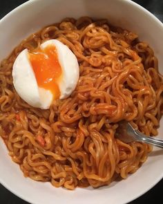 a white bowl filled with noodles and an egg