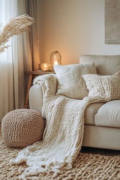 a white couch sitting next to a window with a blanket on it's back