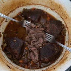 a bowl filled with beef and carrots next to a fork