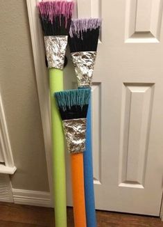 three different colored brushes sitting next to each other in front of a door with tin foil on them